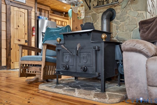 Cast iron wood-burning stove with a decorative pipe, set on a natural stone hearth