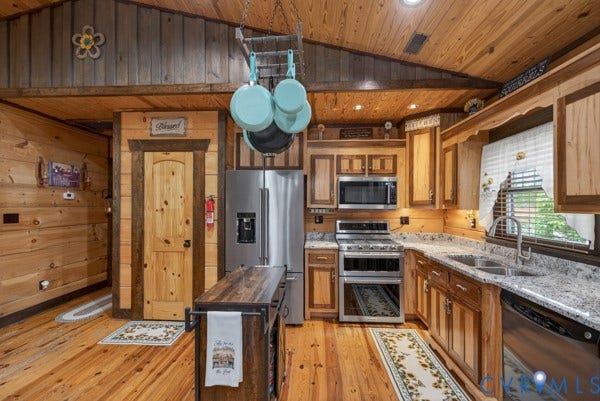 Kitchen featuring stainless steel appliances, wood-finish flooring, wood cabinetry, stone countertops, and a wood-paneled vaulted ceiling