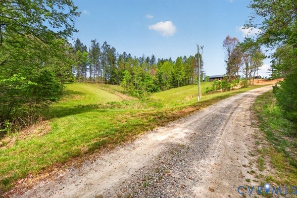 Gravel driveway leading to the property, surrounded by expansive green lawns and mature trees