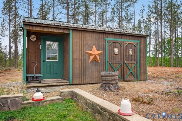 Wood-paneled outbuilding with a green metal roof, a green entry door with window panes, and a set of green barn doors