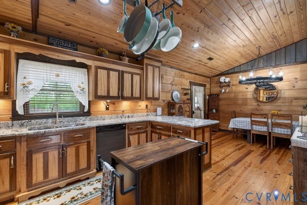Wood walls and ceiling, wood-finish flooring, two-tone wood cabinetry, light-toned countertops, and a dining area with a circular chandelier