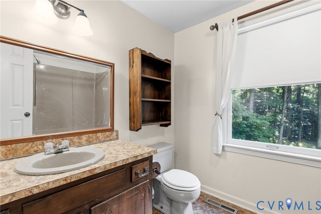 7847 Beaver Drive, All Others Area 20, Gloucester, VA 23061 Vanity with an integrated sink, a rectangular mirror, a two-light fixture, and a window with roller shade