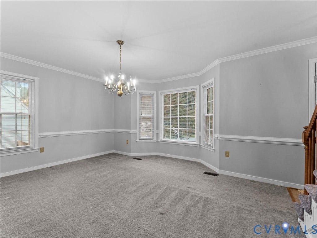 Interior space featuring crown molding, chair rail trim, a bay window, and a multi-arm chandelier