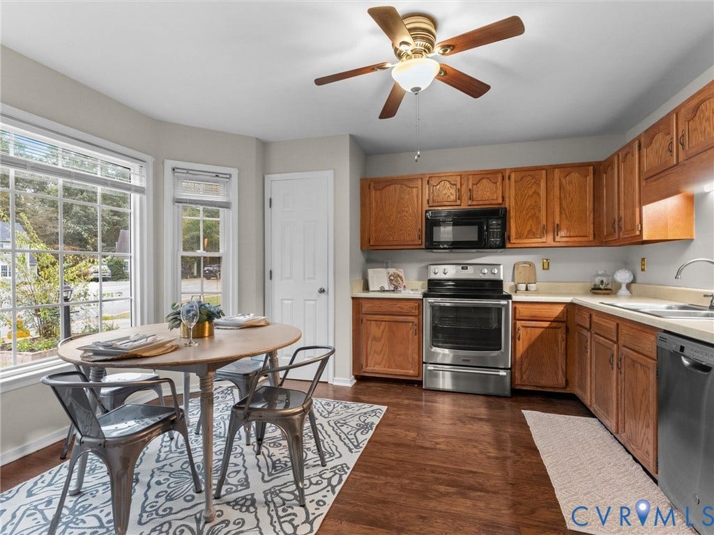Kitchen featuring oak-finish cabinetry, stainless steel appliances, wood-finish flooring, and a bay window