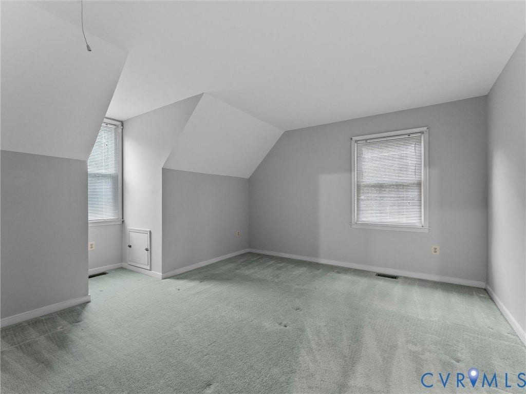 Room featuring neutral wall tones, carpet flooring, vaulted ceilings, and two windows