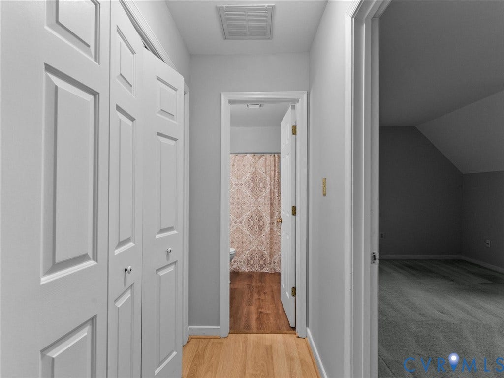 Hallway featuring paneled bi-fold closet doors, light-toned wood-finish flooring, and neutral wall paint