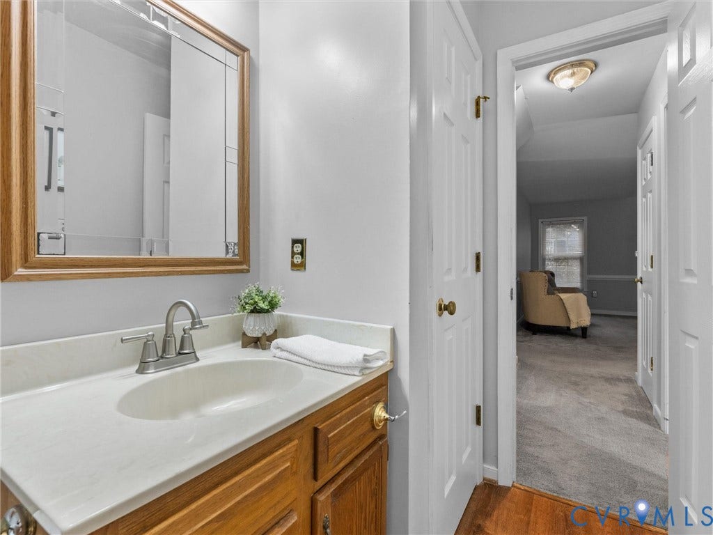 Vanity featuring a wood cabinet, integrated solid-surface countertop with an oval basin, and a framed wall mirror, accompanied by metallic faucet hardware