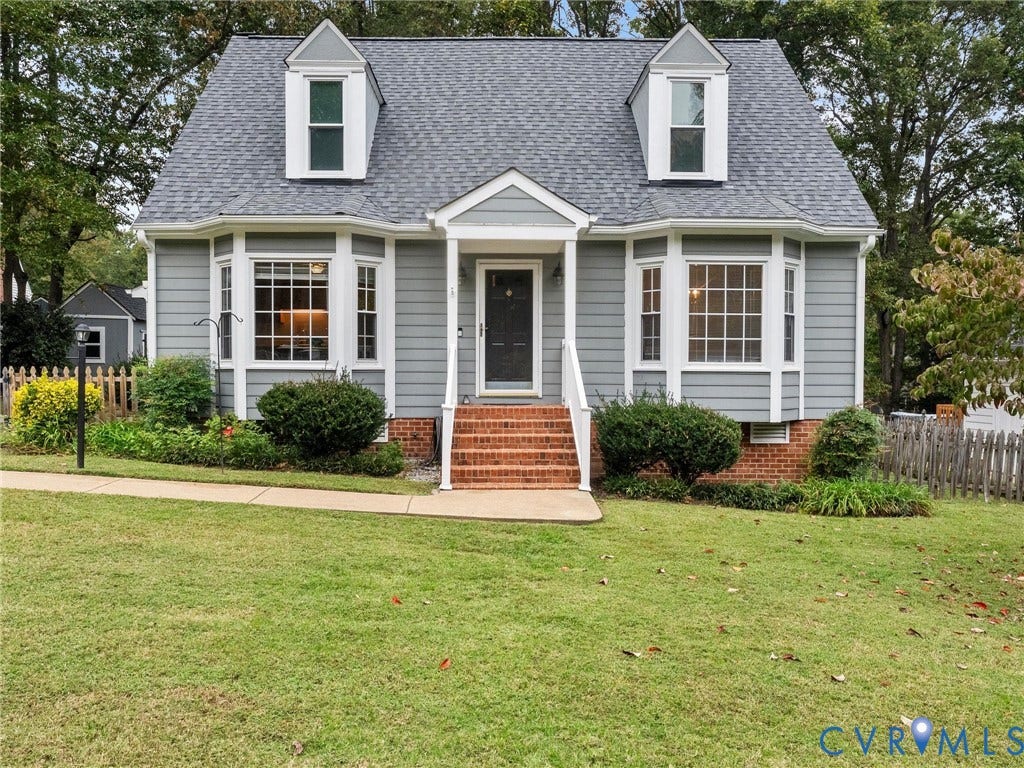 Cape Cod-style residence featuring horizontal siding, twin dormer windows, dual bay windows, and a brick-stair entry with a covered porch