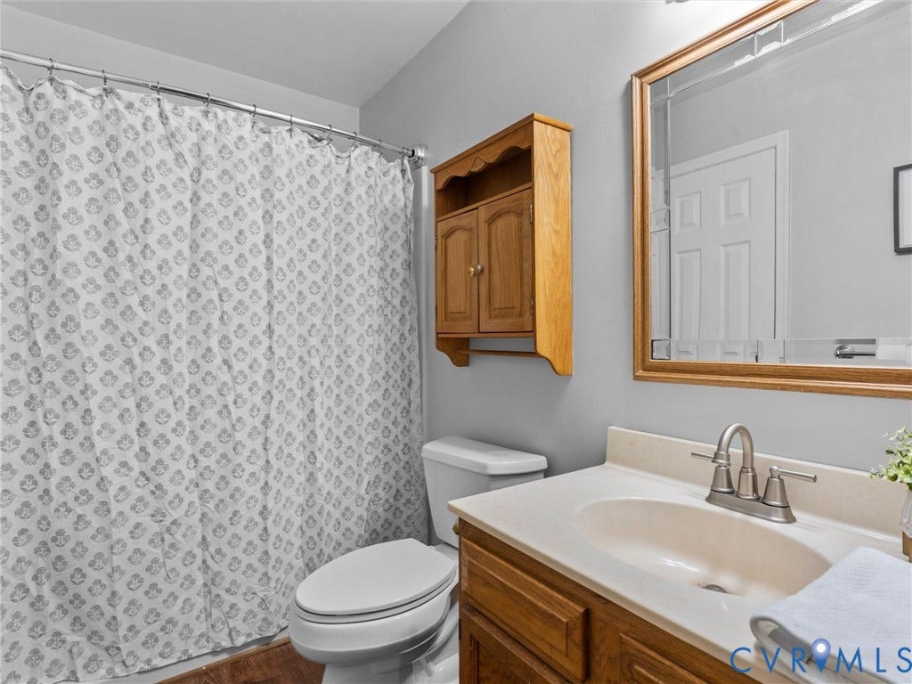 Bathroom featuring a wooden vanity, integrated countertop with sink, wall-mounted wooden cabinet, and a framed mirror