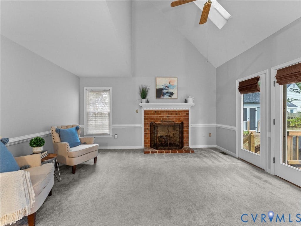 Vaulted ceiling with a central paddle fan, exposed brick fireplace featuring a classic mantel, chair rail molding, and dual glass-panel doors