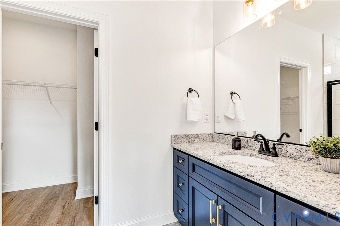 Blue vanity with gold hardware, white undermount sink, and speckled countertop