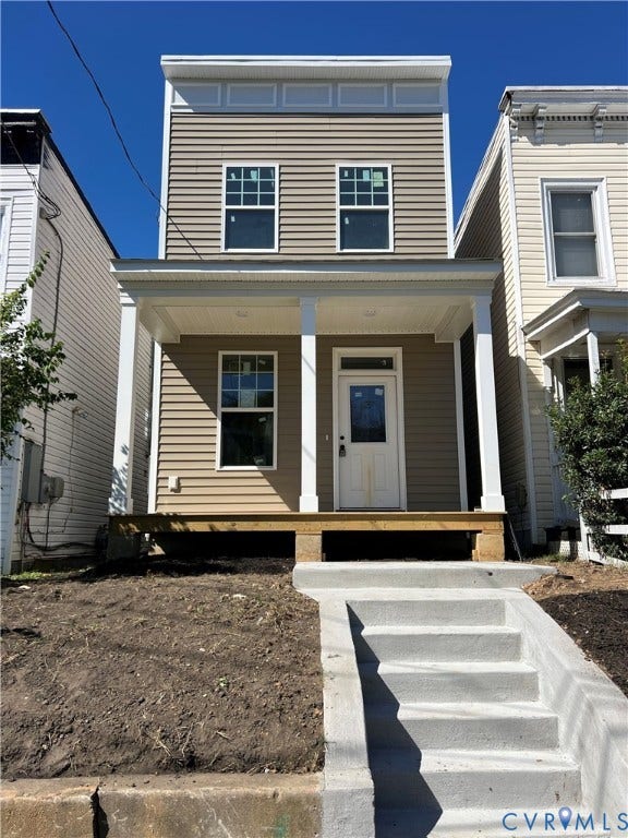 Newly constructed residence featuring a front porch with white columns, light-colored siding, and concrete front steps
