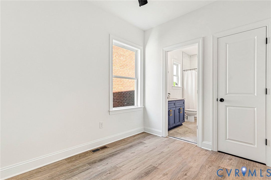 Wood-finish flooring, white walls, and a window providing natural light