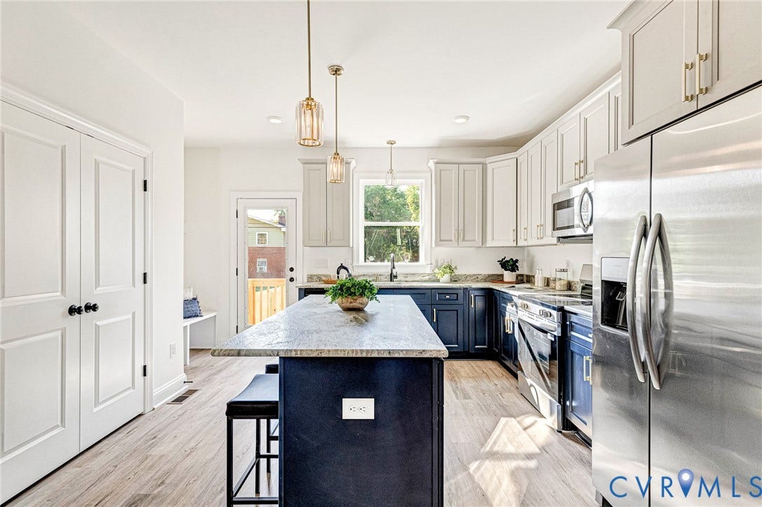Kitchen featuring wood-finish flooring, two-tone cabinetry, stainless steel appliances, a center island with countertop, and pendant lighting