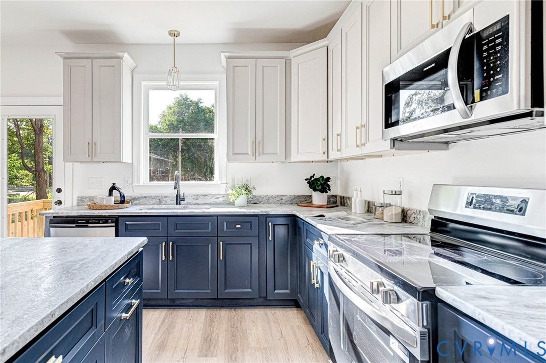 Two-tone cabinetry with gold-finish hardware, stainless steel appliances, wood-finish flooring, light-colored countertops, and a built-in microwave