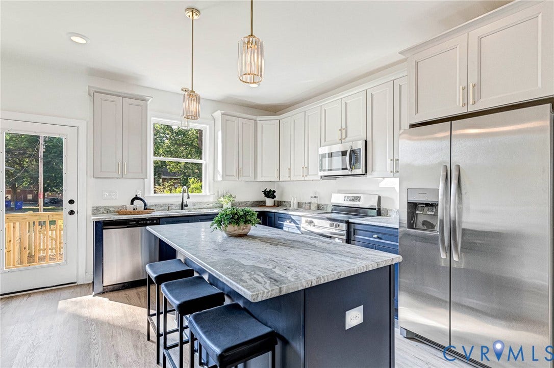 Kitchen featuring a contrasting island, stainless steel appliances, pendant lighting, and wood-finish flooring