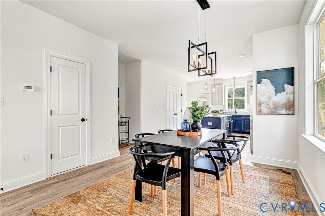 Open-concept dining area featuring wood-finish flooring, a contemporary chandelier, and ample natural light