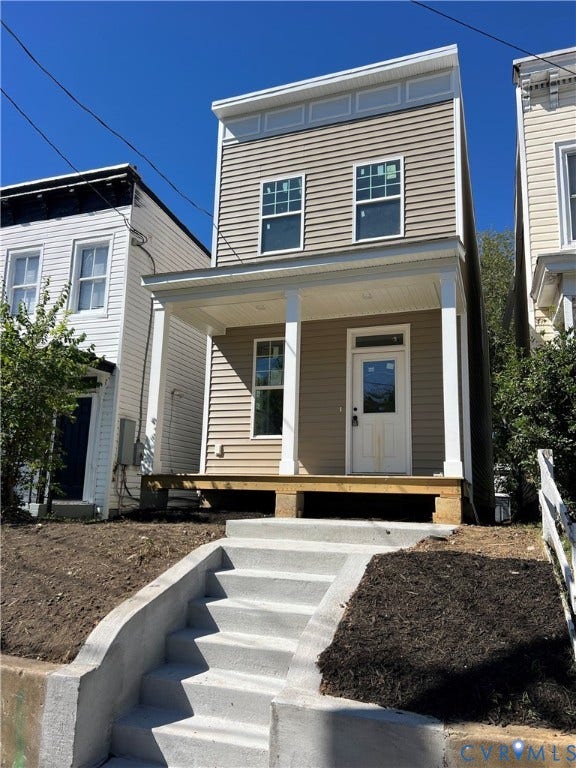 Two-story exterior with horizontal siding, a covered front porch supported by square columns, and a concrete staircase with retaining walls