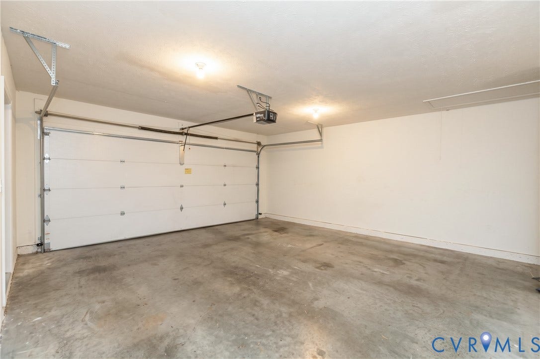Attached garage with a sectional overhead door, automatic opener, and concrete flooring