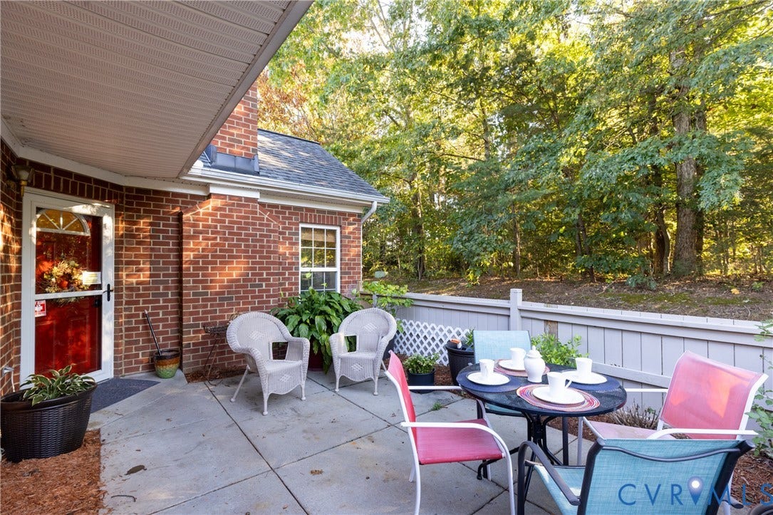 Brick exterior with a covered patio, concrete surface, and a privacy fence