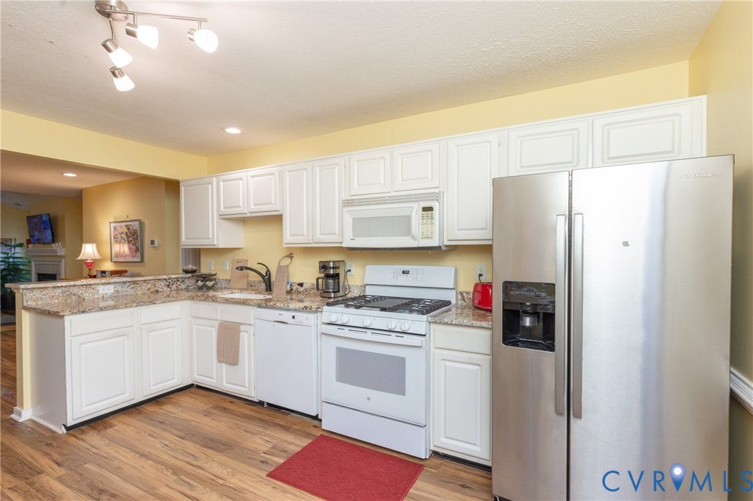 Kitchen featuring white cabinetry, granite countertops, wood-finish flooring, stainless steel side-by-side refrigerator, and white built-in appliances