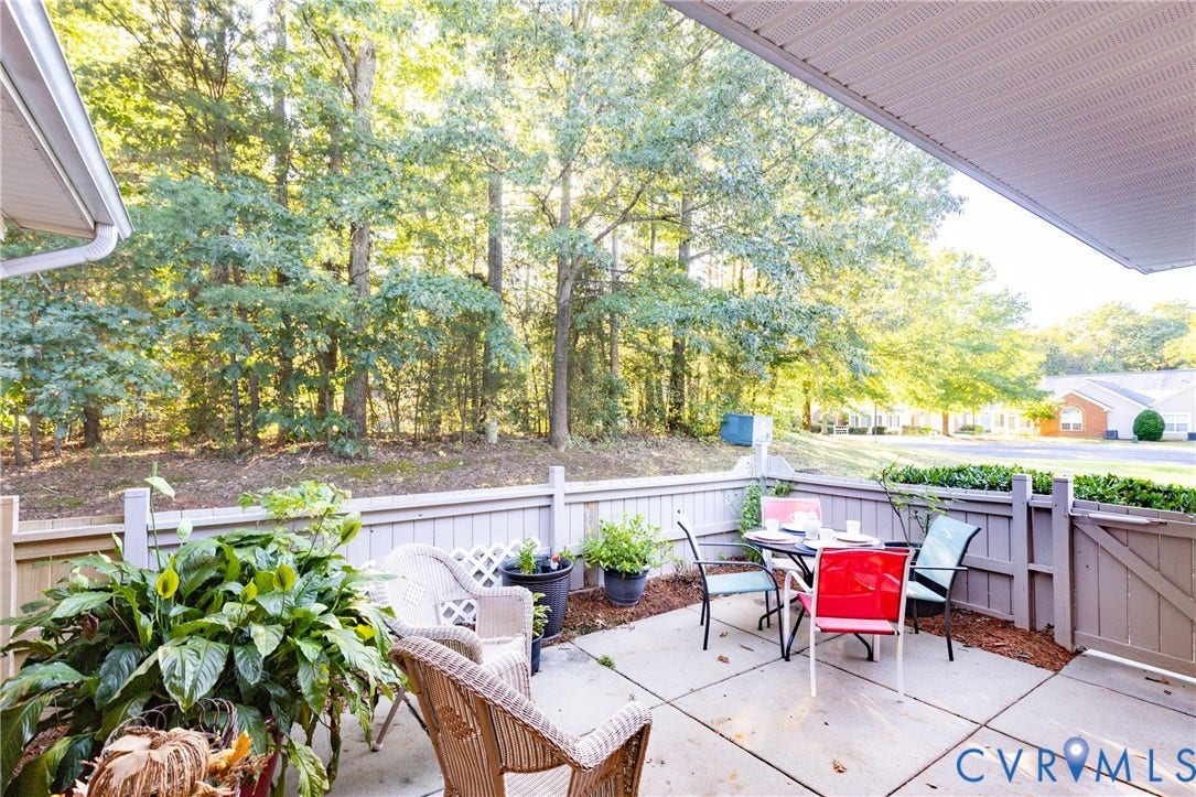 Private patio area featuring concrete paving, a slatted fence, and a gate