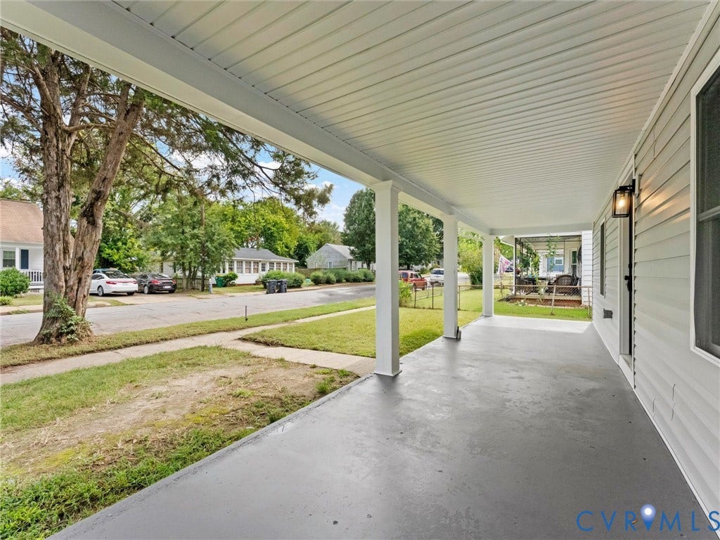 Expansive covered porch with a painted concrete floor, white support columns, and horizontal vinyl siding exterior