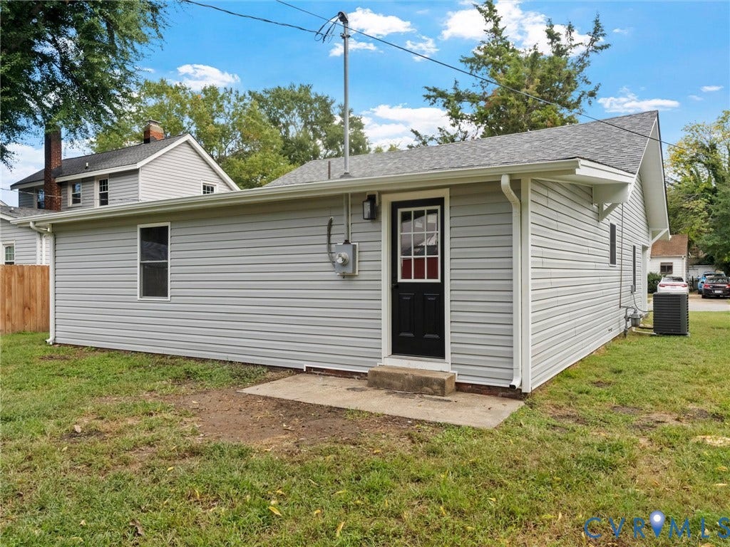 Light gray horizontal siding with a black paneled door and a concrete landing