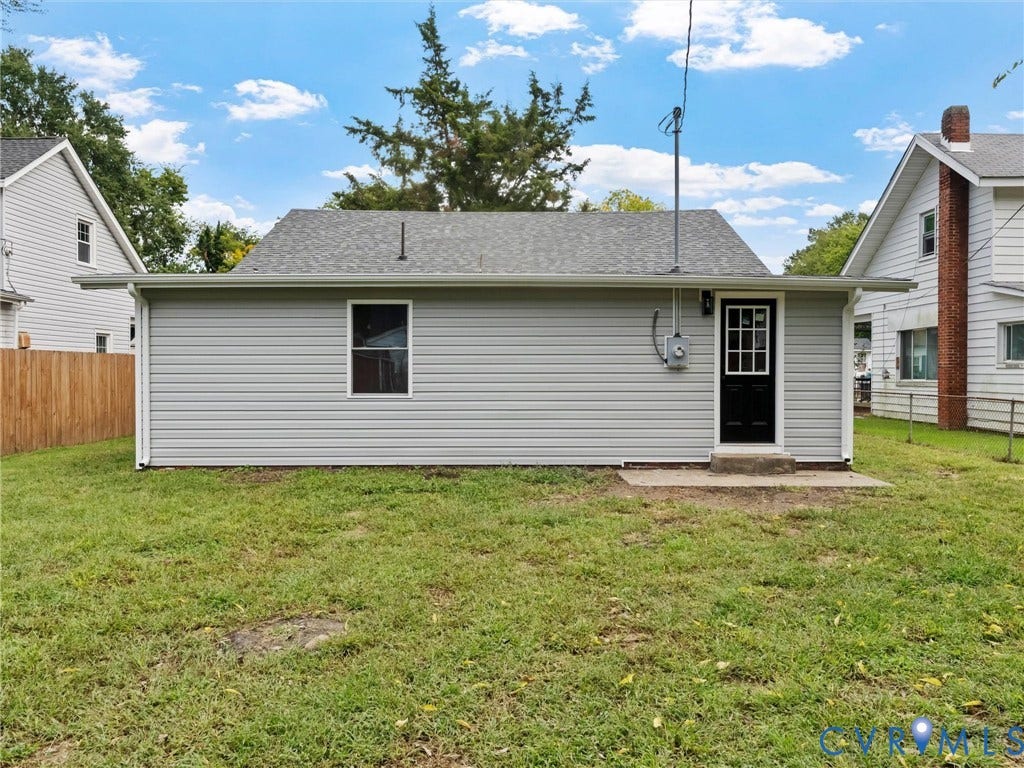 Gray siding exterior with white trim, a black paneled door, and a single window