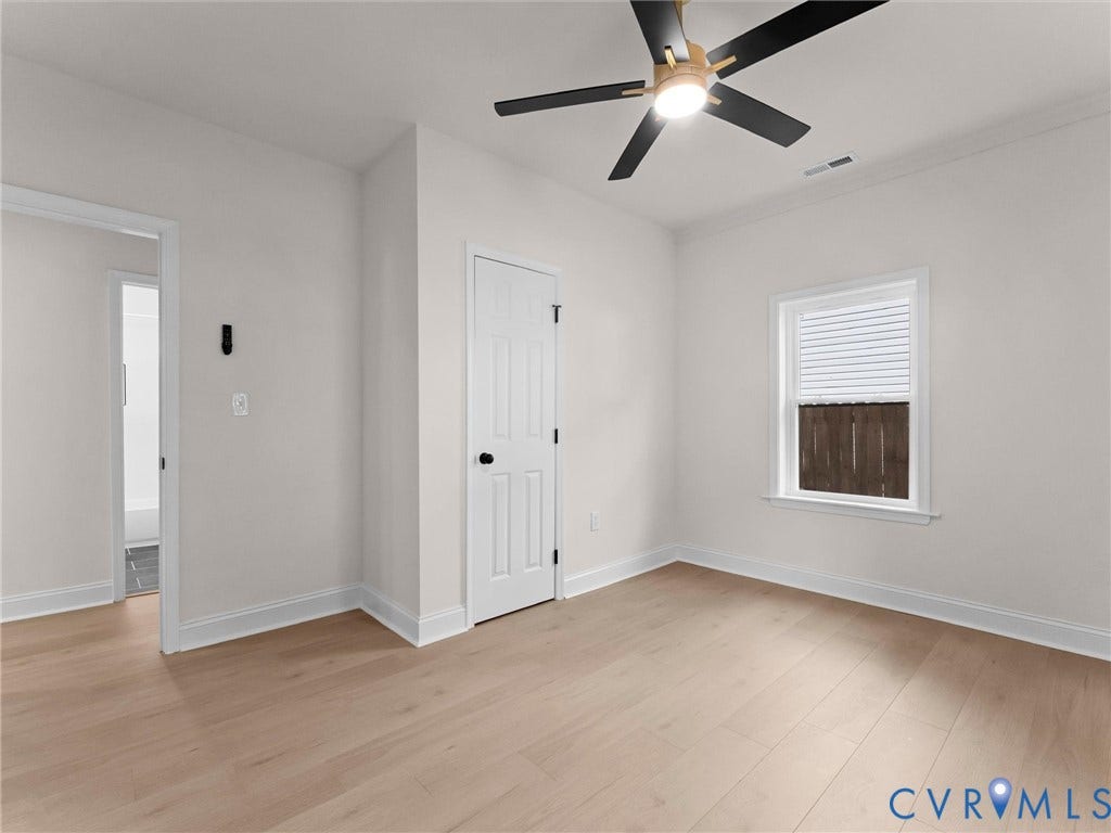 Light wood-finish flooring, a modern ceiling fan with integrated lighting, and a window with blinds