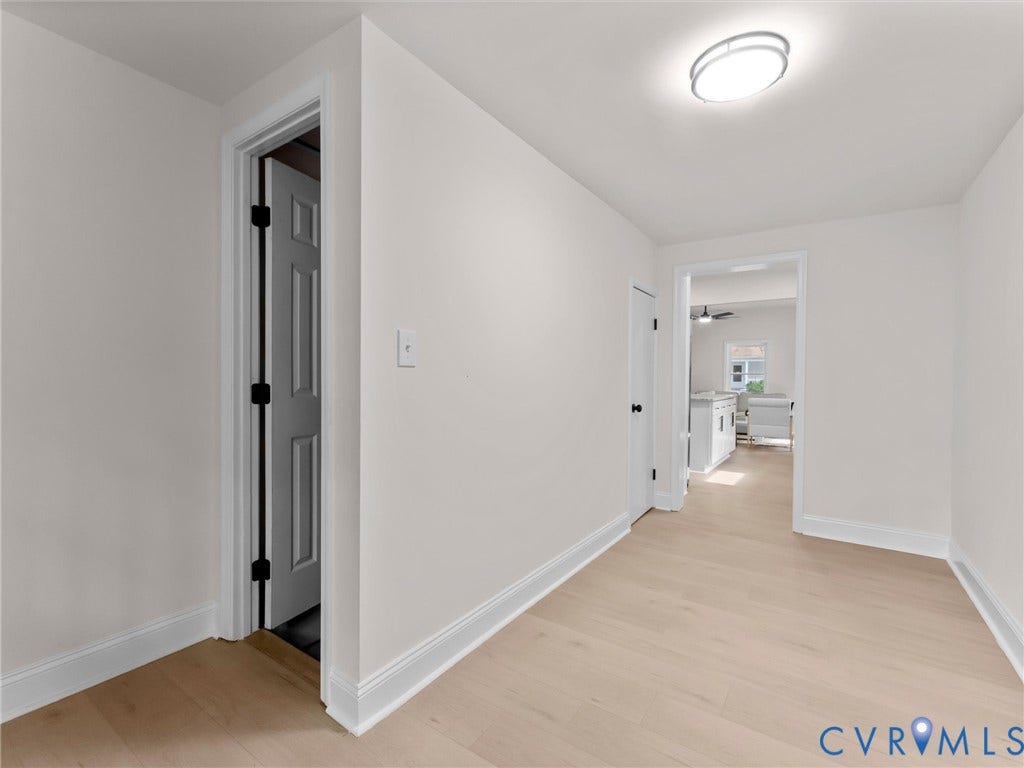 Light wood-finish flooring, white painted walls, white trim, recessed lighting, and panel doors
