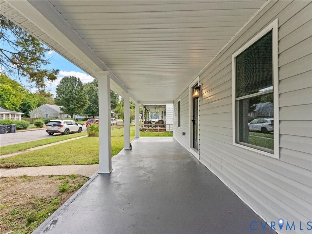 Expansive covered porch with a gray-painted concrete floor and white support columns