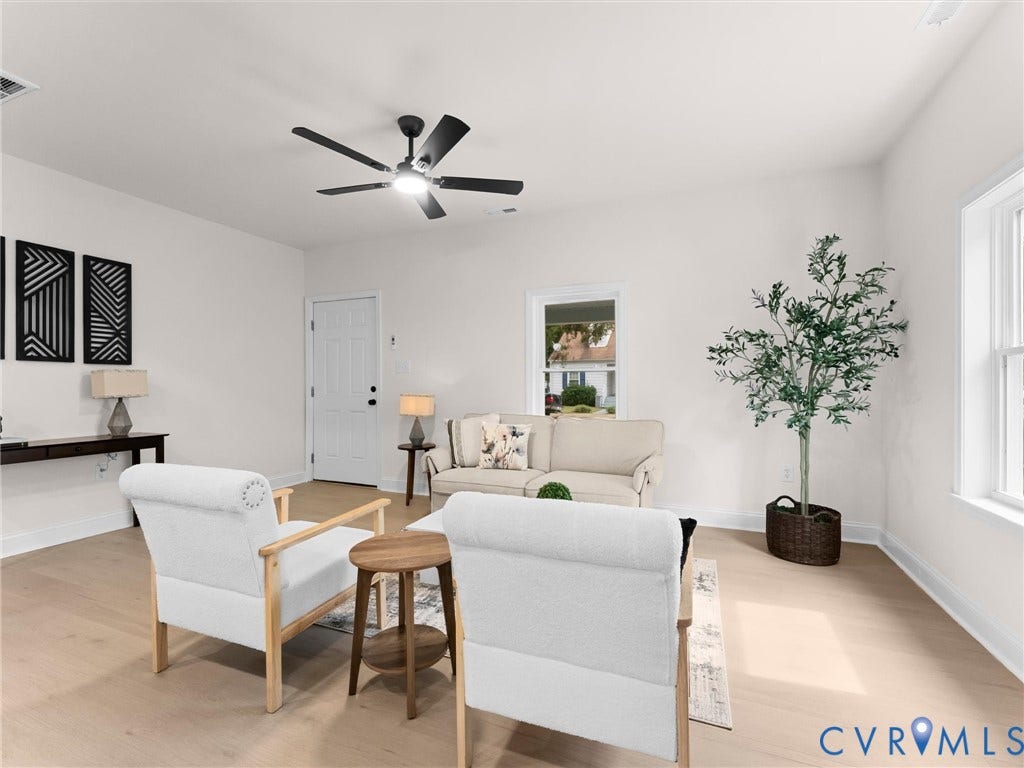 Open-concept living space featuring wood-finish flooring, a contemporary ceiling fan, and a white paneled door