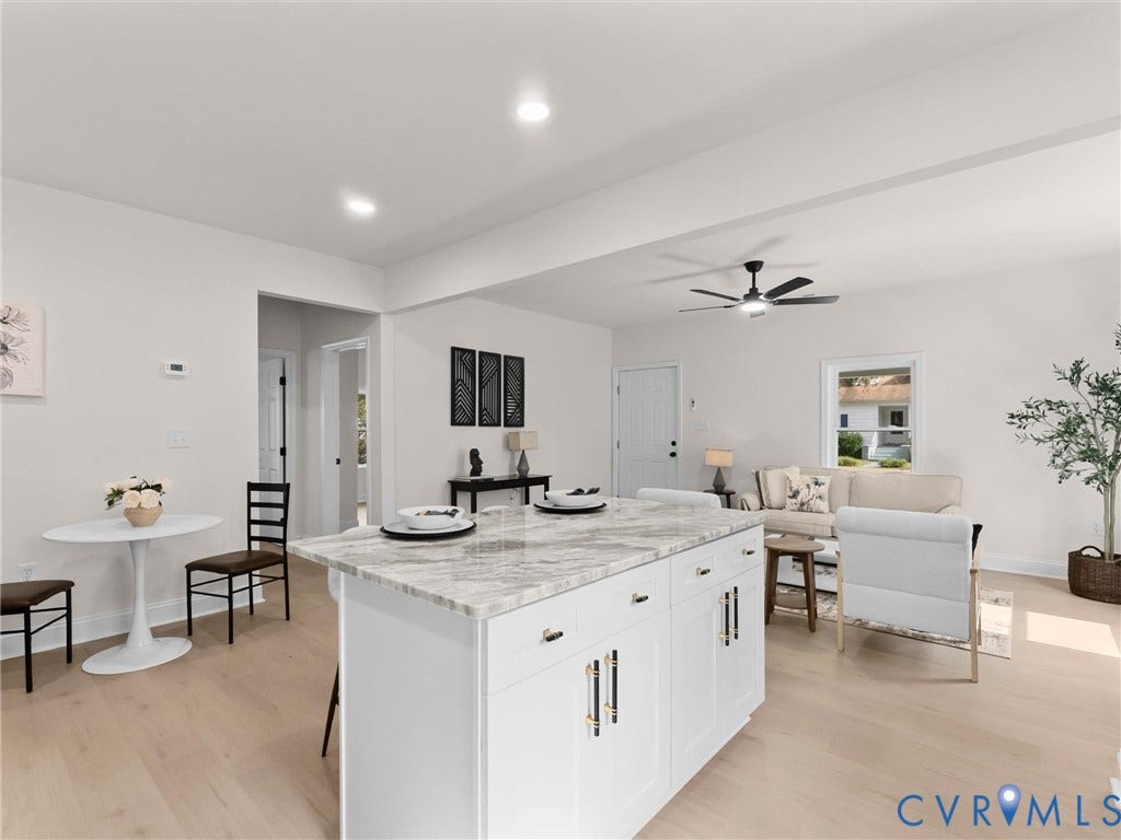 Open-concept living space featuring a kitchen island with stone countertop, recessed lighting, and light wood-finish flooring