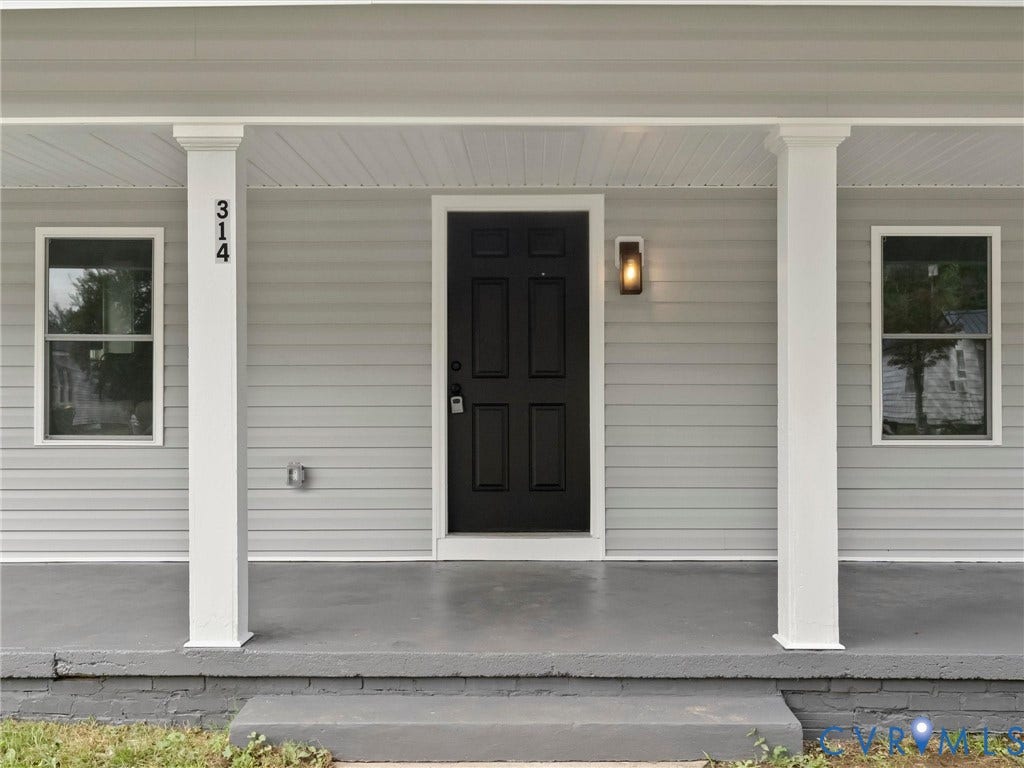 Covered porch with square white columns, gray siding, and a contrasting black entry door