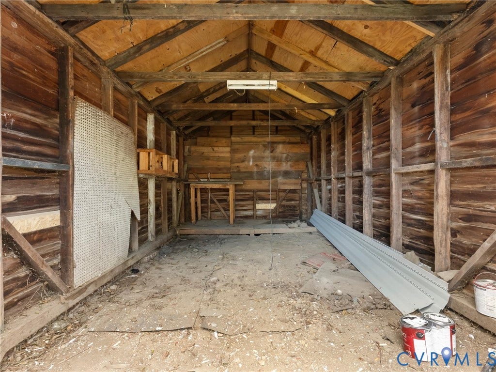 Wood-clad interior walls with exposed wood framing, a vaulted ceiling with exposed rafters, and a built-in workbench