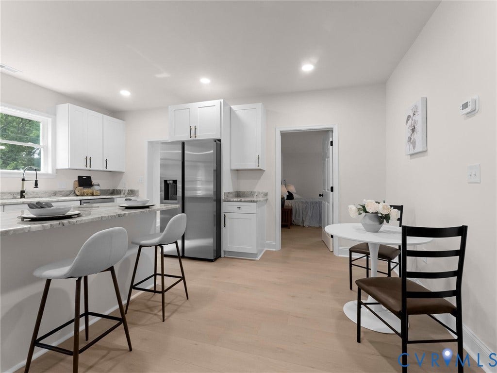 Bright kitchen with white cabinetry, light countertops, stainless steel refrigerator, and recessed lighting