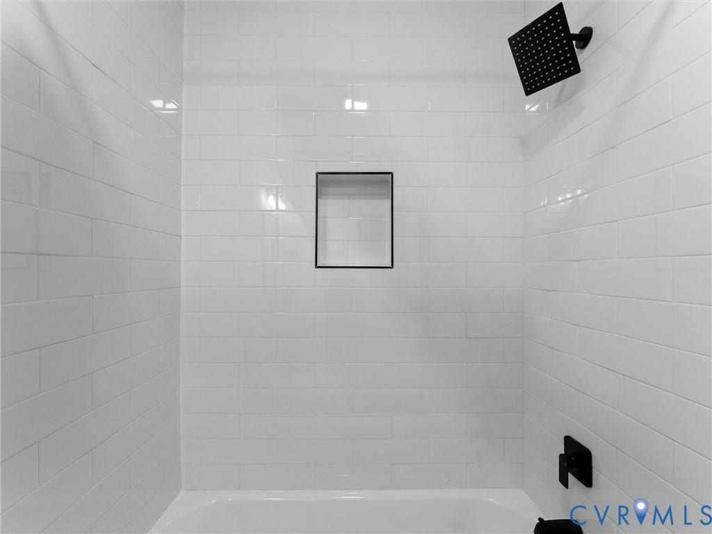 White subway tile surround with a built-in niche, matte black rainfall showerhead, and coordinating bath fixtures