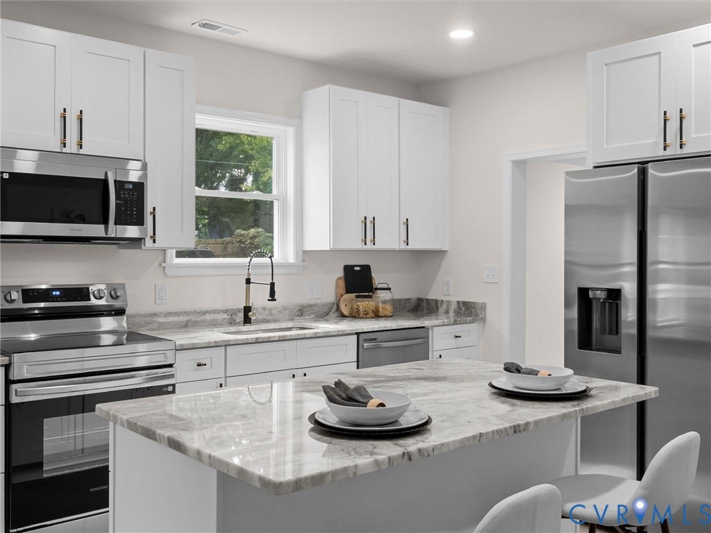 Kitchen featuring white shaker cabinetry, stainless steel appliances, a center island, recessed lighting, and stone countertops