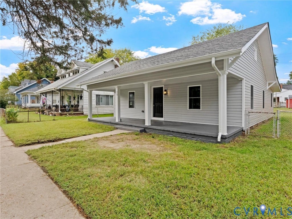 Exterior featuring light grey siding, a covered front porch, a dark grey porch floor, a black entry door, and a grey shingled roof