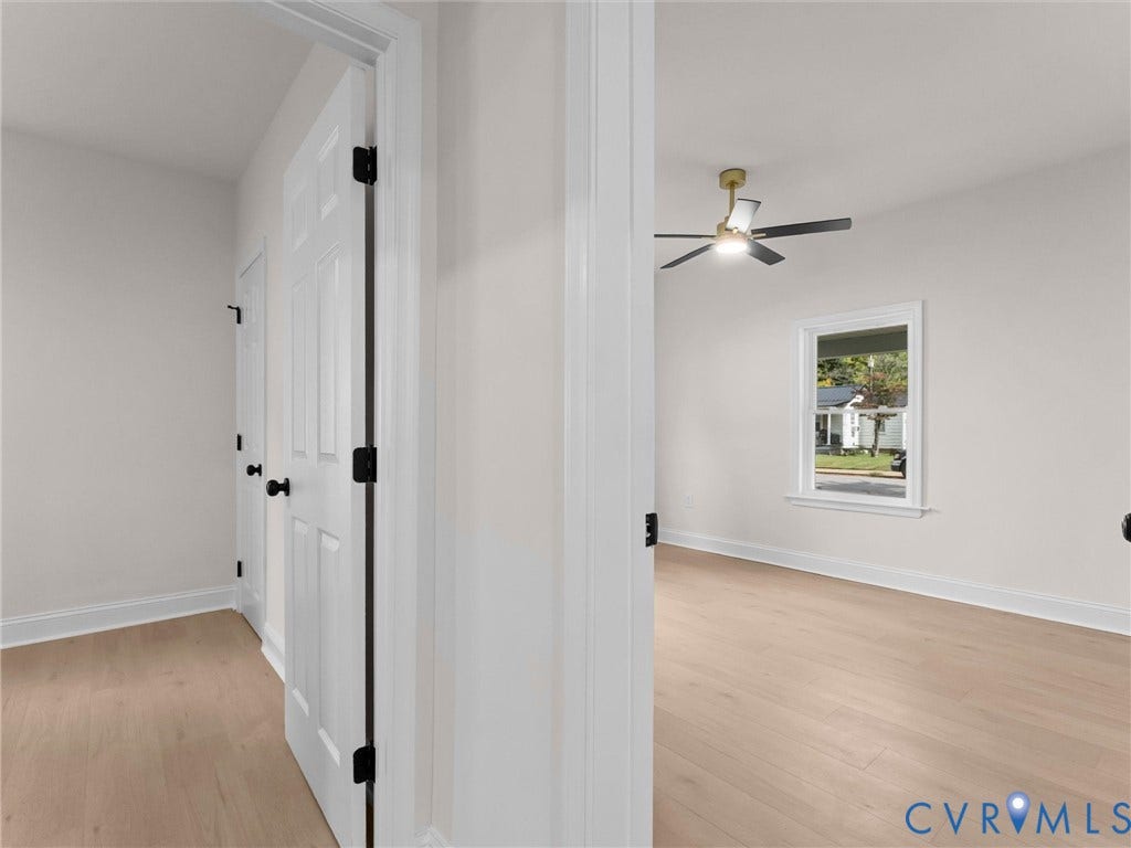 Light-toned wood-finish flooring, white trim, and a ceiling fan with integrated lighting