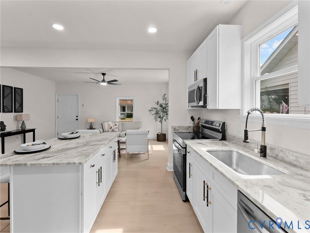 Kitchen featuring white cabinetry, stone countertops, stainless steel appliances, and a kitchen island with seating