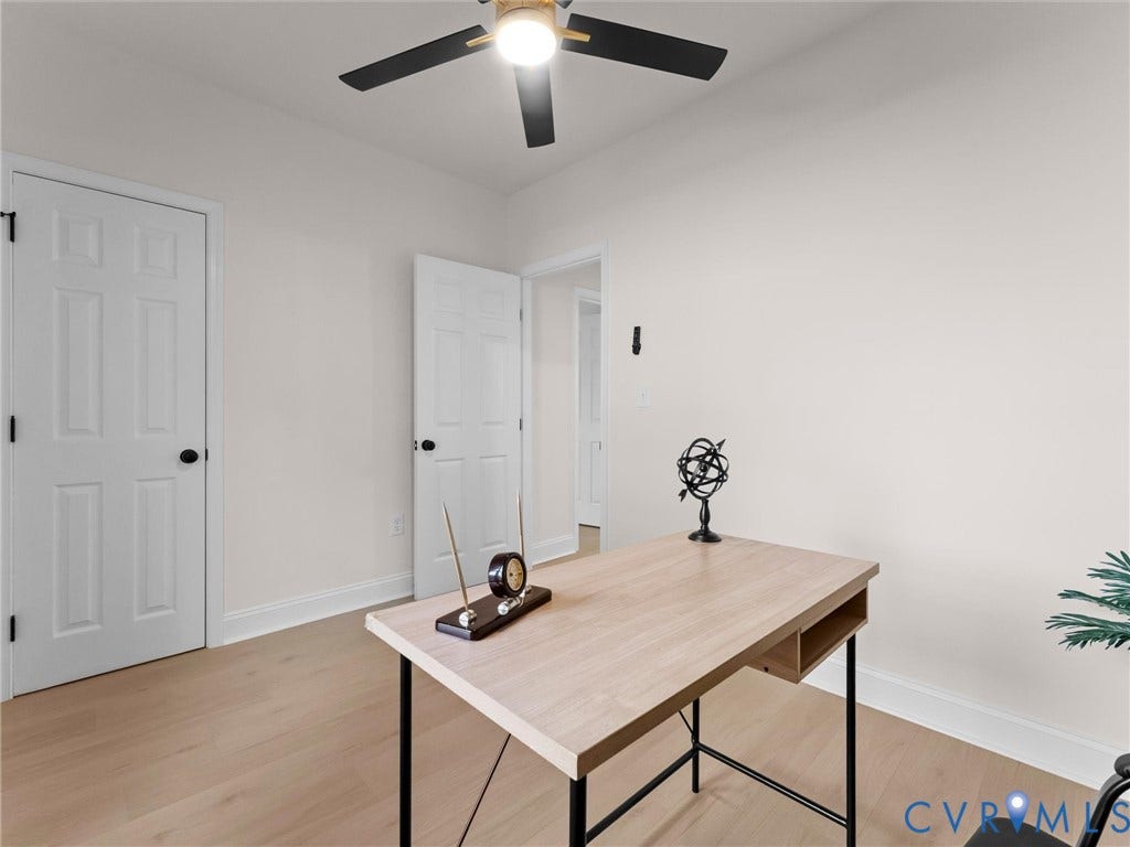 Bright home office featuring warm wood-finish flooring, ceiling fan with integrated lighting, and clean white six-panel doors
