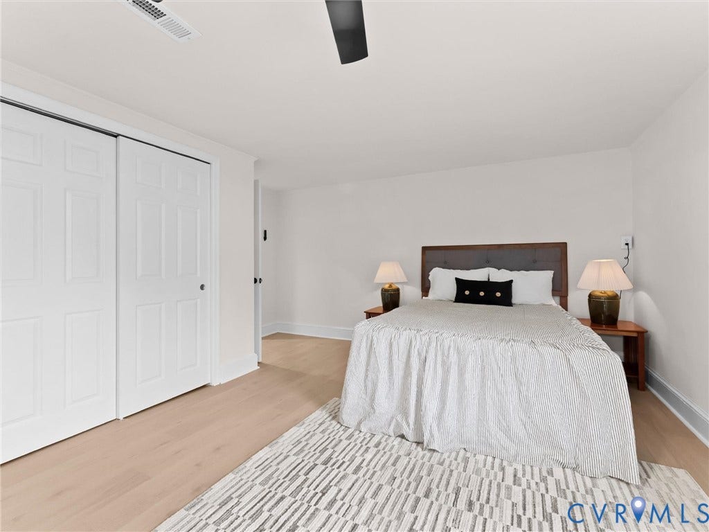 Light wood-finish flooring, white walls, and a ceiling fan