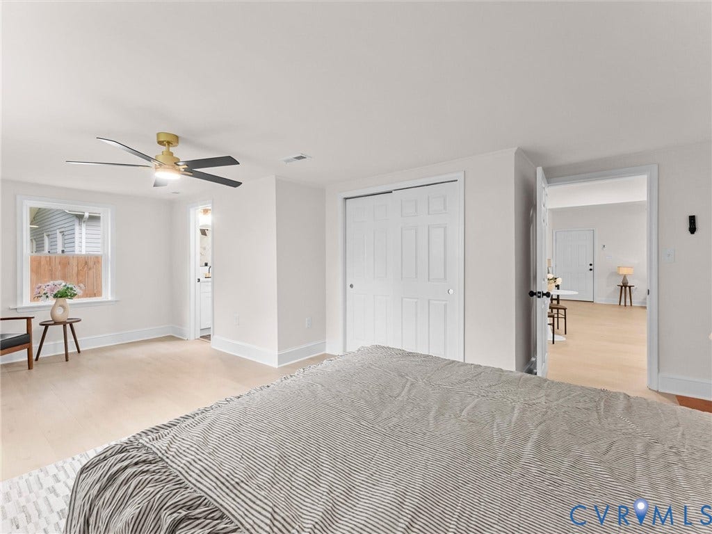 Light-toned wood-finish flooring, a contemporary ceiling fan with integrated lighting, a sliding door closet, and a white paneled door