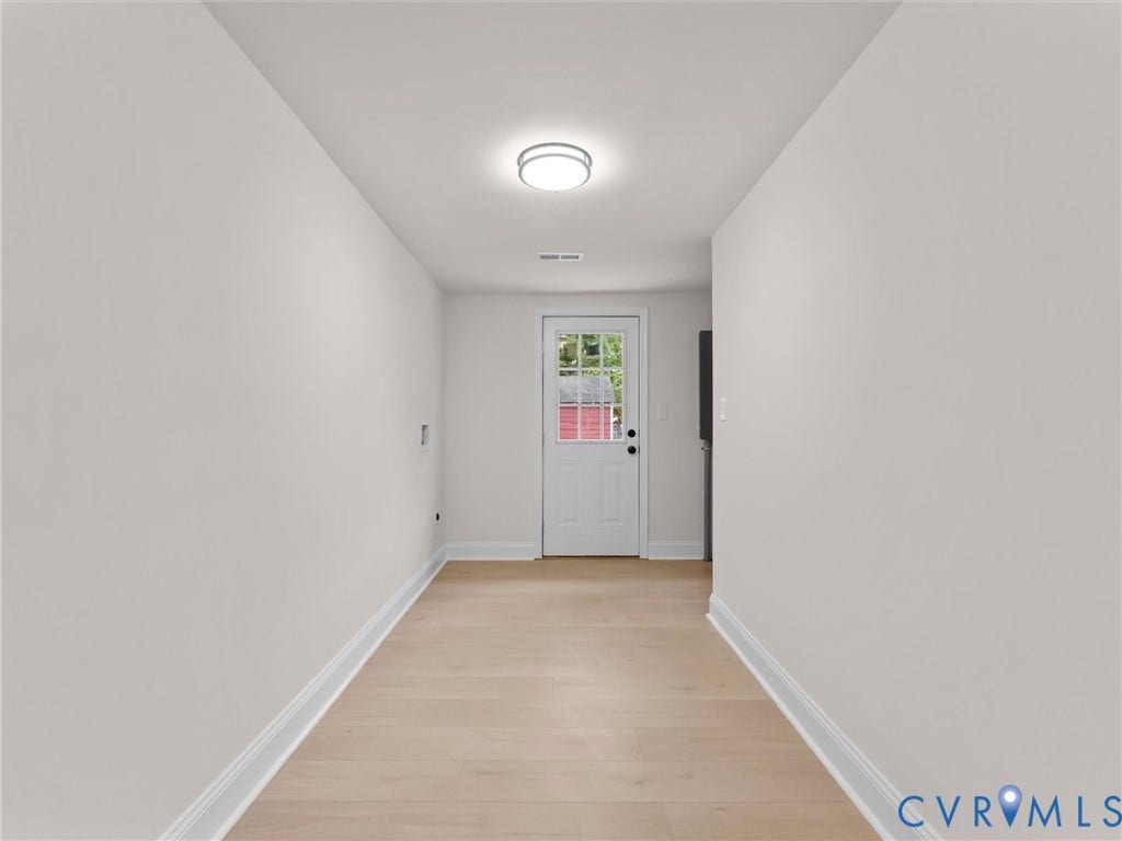 Light wood-finish flooring with white baseboards, white walls, and a recessed ceiling light