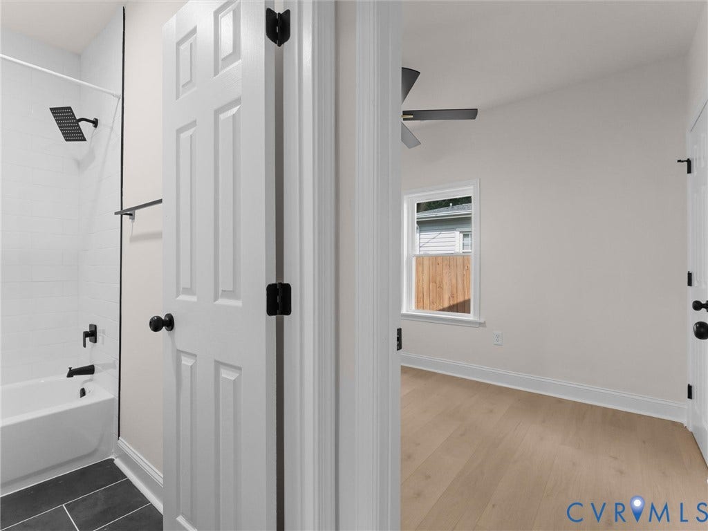 Bathroom featuring white subway tile surround, matte black shower fixtures, and dark tile flooring