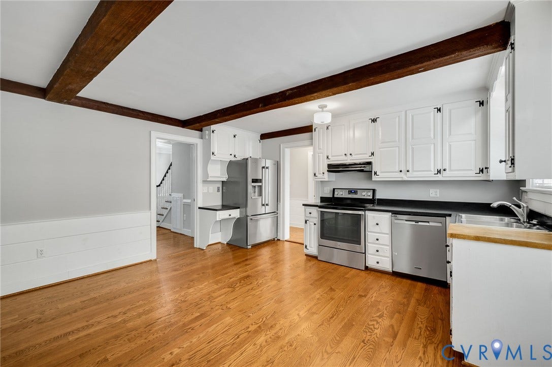 10303 Silverbrook Drive, Henrico, VA 23233 Hardwood flooring throughout, exposed wood ceiling beams, white cabinetry with black hardware, stainless steel appliances, and a built-in desk area