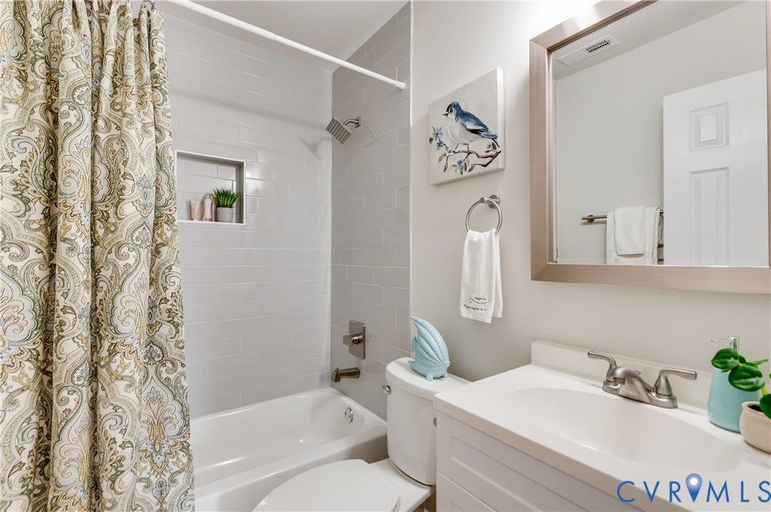 8010 Callison Drive, Glen Allen, VA 23060 Built-in bathtub with subway tile surround, recessed shower niche, single vanity with integrated sink, and framed mirror
