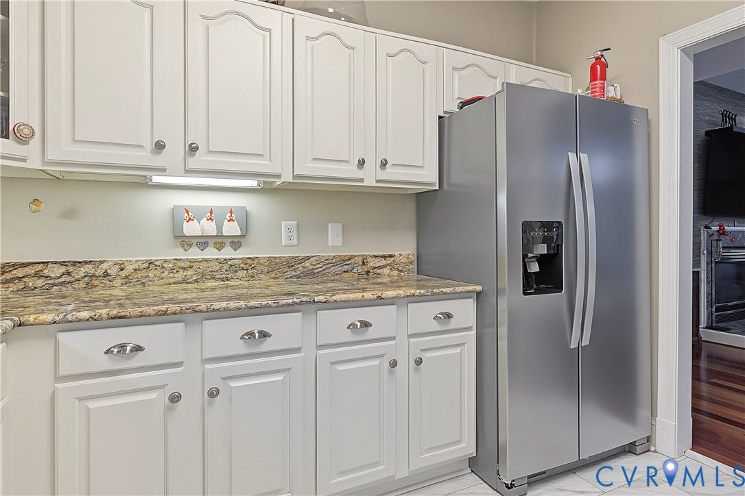 3131 Stony Point Road, #B, Richmond, VA 23235 White cabinetry with brushed nickel hardware, natural stone countertops, under-cabinet lighting, and a stainless steel side-by-side refrigerator
